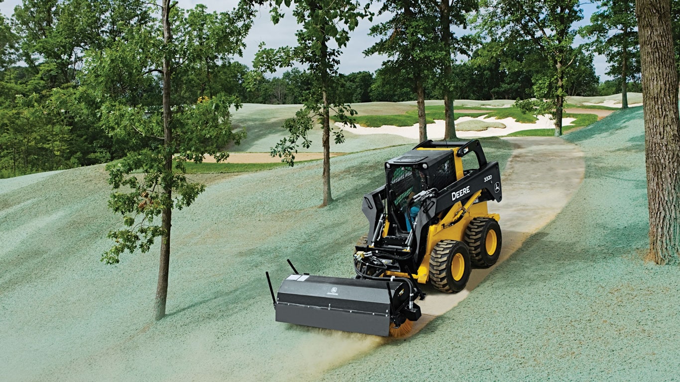 John Deere Skid Steer with angle broom attachment sweeping a pathway.